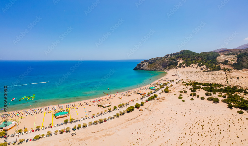 Aerial birds eye view drone photo Tsambika beach near Kolympia on Rhodes island, Dodecanese, Greece. Sunny panorama with sand beach and clear blue water. Famous tourist destination in South Europe Aerial birds eye view drone photo Tsambika beach near Kolympia on Rhodes island, Dodecanese, Greece. Sunny panorama with sand beach and clear blue water. Famous tourist destination in South Europe