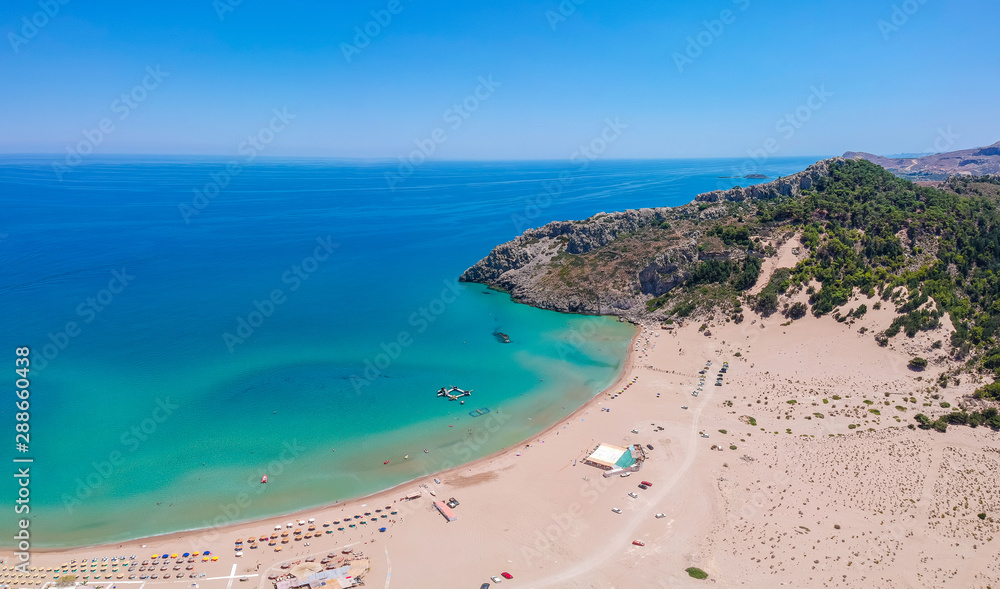 Aerial birds eye view drone photo Tsambika beach near Kolympia on Rhodes island, Dodecanese, Greece. Sunny panorama with sand beach and clear blue water. Famous tourist destination in South Europe
