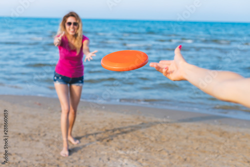 Cuadro en lienzo Millennials girls playing on the beach, focus on red frisbee
