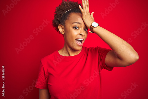 Young beautiful african american woman with afro hair over isolated red background surprised with hand on head for mistake, remember error. Forgot, bad memory concept.