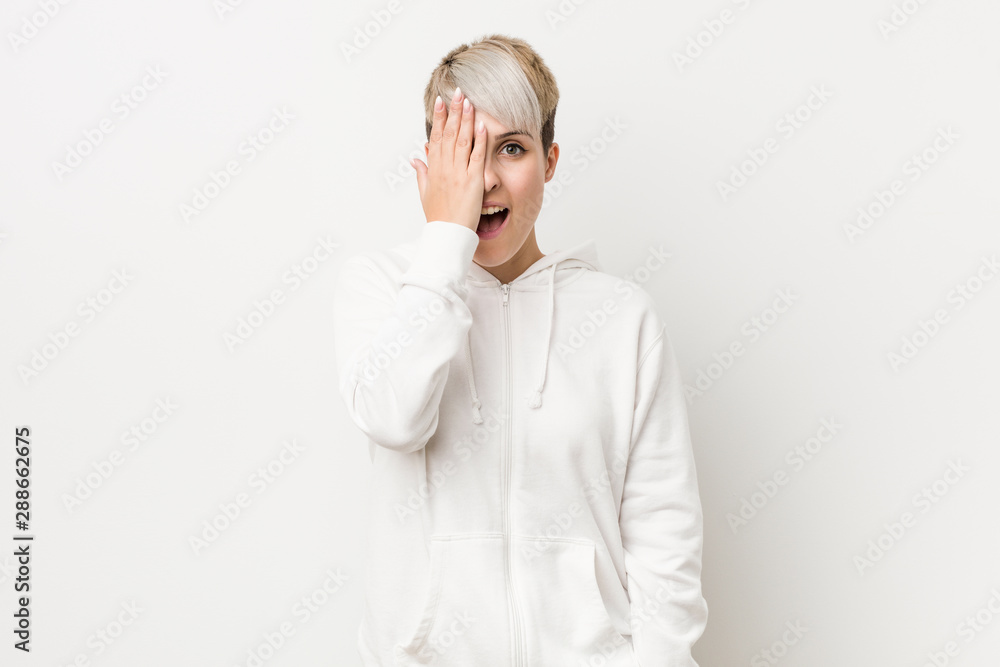 Young curvy woman wearing a white hoodie having fun covering half of face with palm. Young curvy woman wearing a white hoodie having fun covering half of face with palm.