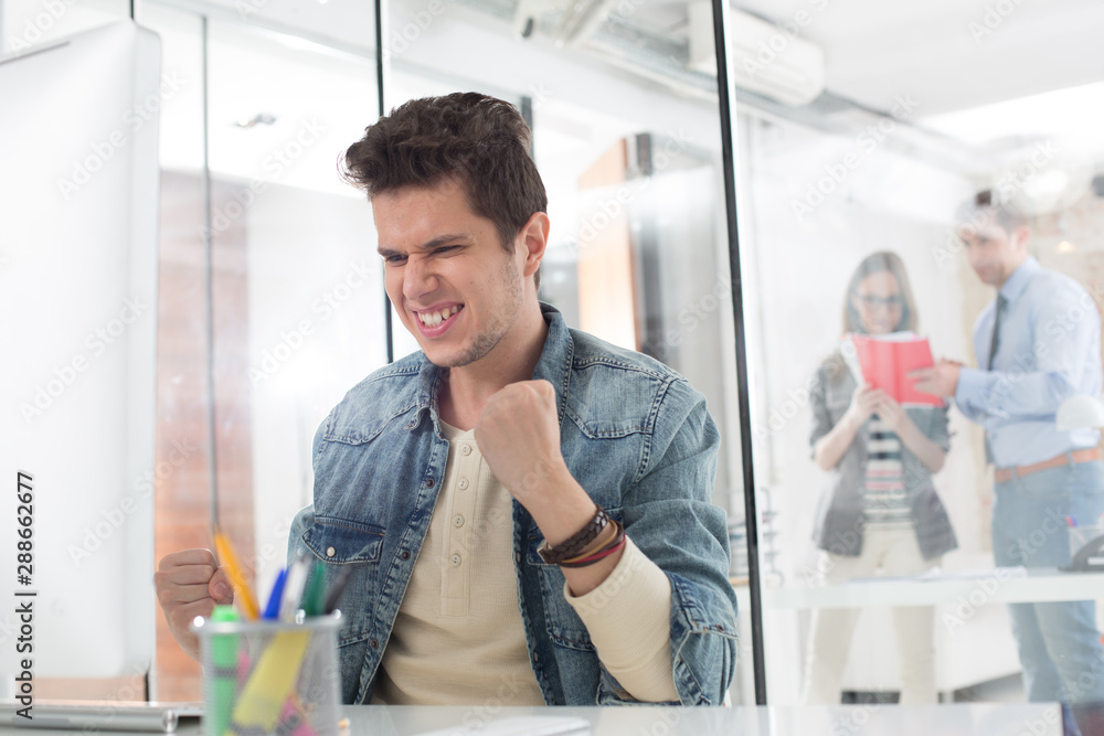 Excited businessman celebrating success at computer desk in office Excited businessman celebrating success at computer desk in office
