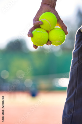 Photo of senior man holding tennis balls on court