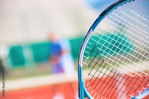 Photo of tennis racket against friend playing match on court