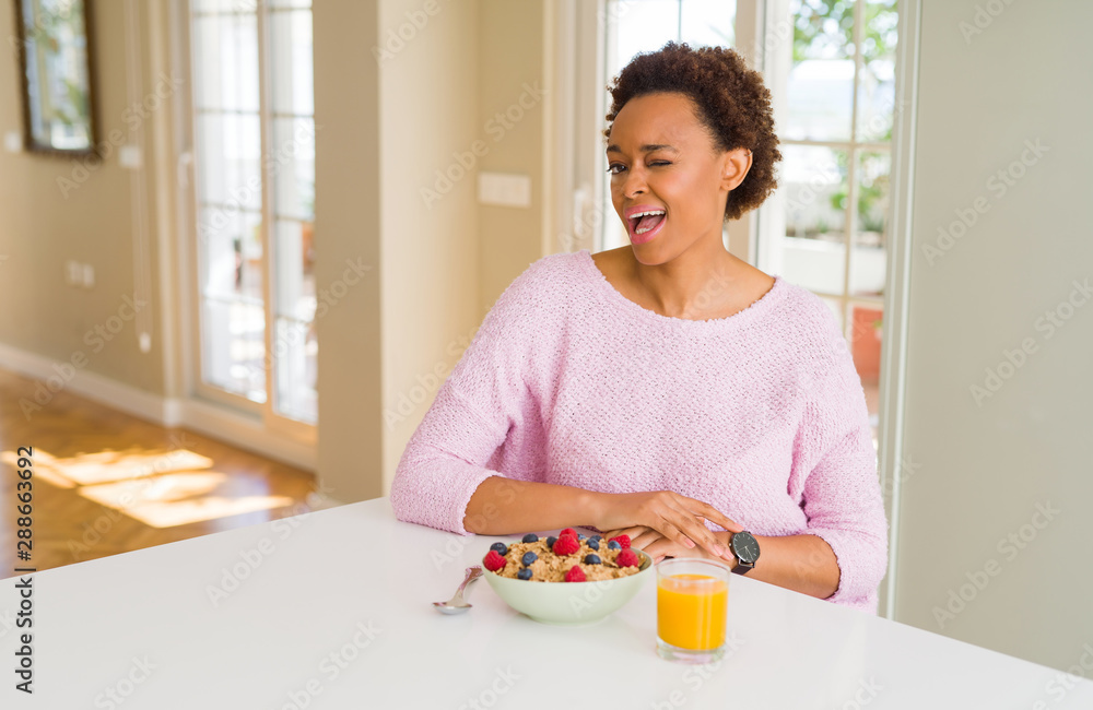 Young african american woman having healthy breakfast in the morning at home winking looking at the camera with sexy expression, cheerful and happy face. Young african american woman having healthy breakfast in the morning at home winking looking at the camera with sexy expression, cheerful and happy face.