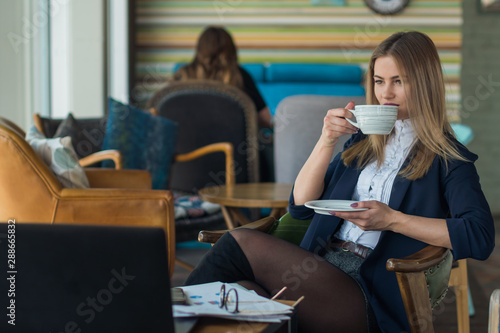 Young attractive girl drinking coffee in a cafe during a business lunch
