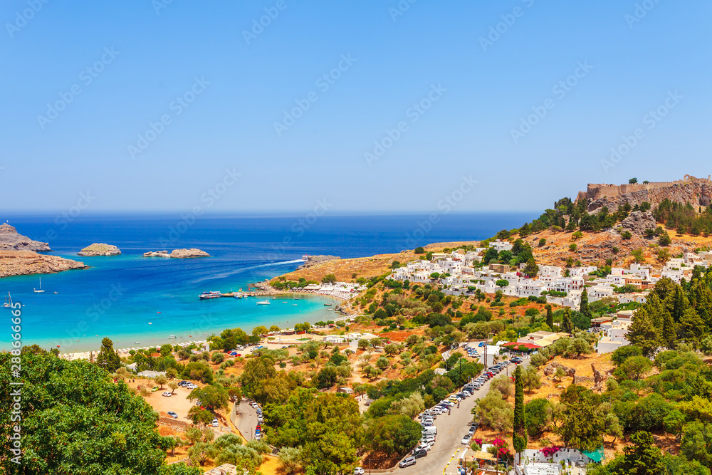 Sea skyview landscape photo Lindos bay and castle on Rhodes island, Dodecanese, Greece. Panorama with ancient castle and clear blue water. Famous tourist destination in South Europe