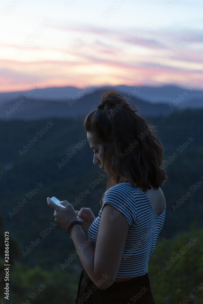 Traveller looking at her phone with mountains in background