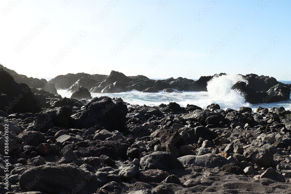 Fototapeta premium Waving crashing into a rock on a beach in Los Gigantes, Spain