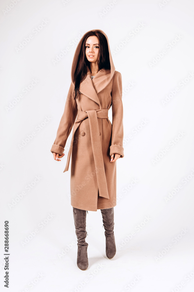 girl in a warm light coat on a white background. model in outerwear. brunette in a long beige coat. beautiful girl in a casual coat. spring autumn collection. Portrait of a brunette coat, full growth. girl in a warm light coat on a white background. model in outerwear. brunette in a long beige coat. beautiful girl in a casual coat. spring autumn collection. Portrait of a brunette coat, full growth.
