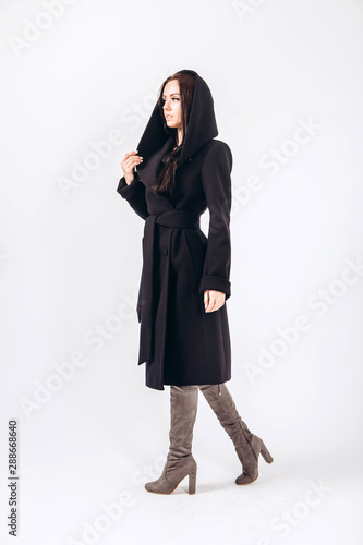 girl in a warm light coat on a white background. model in outerwear. brunette in a long black coat. beautiful girl in a casual coat. spring autumn collection. Portrait of a brunette coat, full growth. © Stanislav