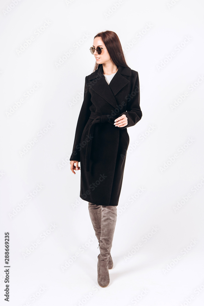 girl in a warm light coat on a white background. model in outerwear. brunette in a long black coat. beautiful girl in a casual coat. spring autumn collection. Portrait of a brunette coat, full growth. girl in a warm light coat on a white background. model in outerwear. brunette in a long black coat. beautiful girl in a casual coat. spring autumn collection. Portrait of a brunette coat, full growth.