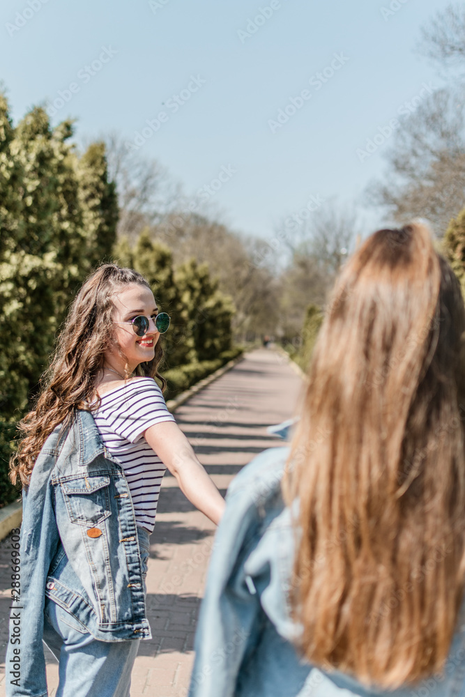 Fototapeta premium Friendship day. Lifestyle image of best friend girls in spring summer city street. Two Teenage girls having fun in the park