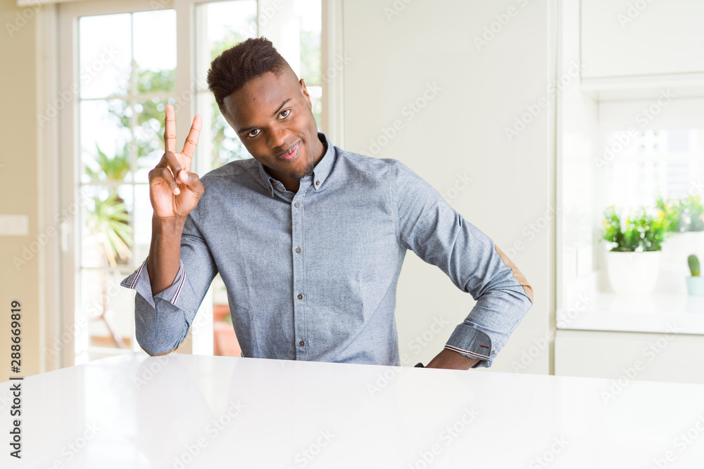 Handsome african american man on white table showing and pointing up with fingers number two while smiling confident and happy. Handsome african american man on white table showing and pointing up with fingers number two while smiling confident and happy.