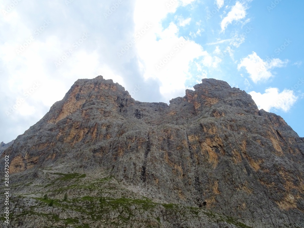 The peaks of the Dolomites of the Sassolungo Massif immersed in the clouds and in the nature of Trentino - Alto - Adige, Near the town of Canazei, Italy - August 2019.