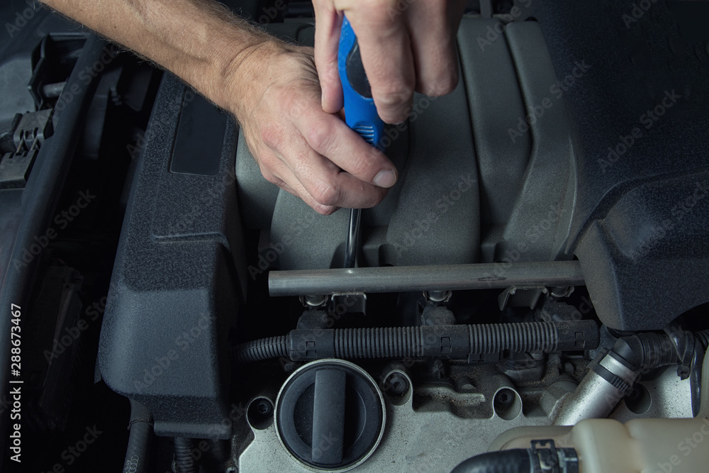 Man fixes car in a car service. Engine repair, maintenance, service