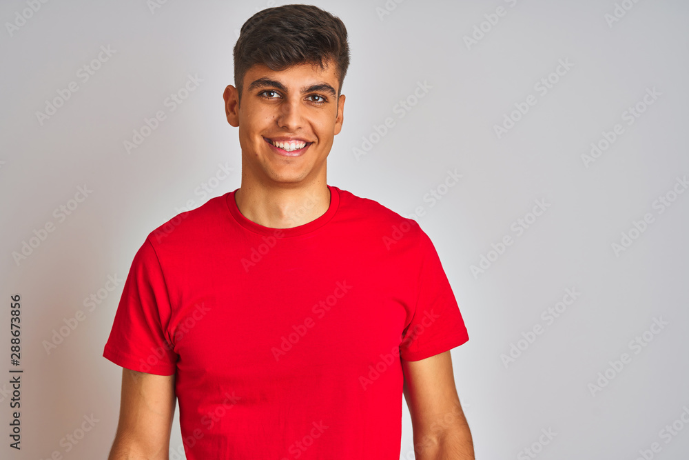 Young indian man wearing red t-shirt standing over isolated white background with a happy and cool smile on face. Lucky person. Young indian man wearing red t-shirt standing over isolated white background with a happy and cool smile on face. Lucky person.
