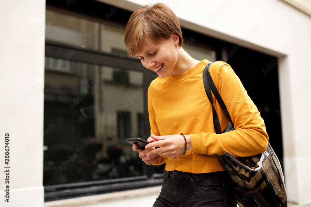 happy young woman walking and looking at text on cellphone happy young woman walking and looking at text on cellphone