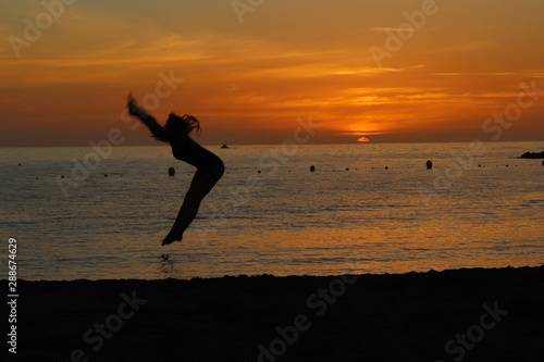 Girl jumps on a beach at sunset in Tenerife  Spain