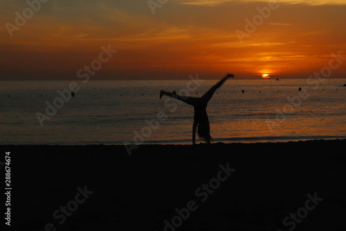 Girl doing cartwheel on a beach in Tenerife, Spain at sunset