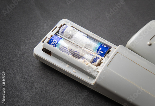 Remote control with old battery leak on dark background. Hazardous waste concept