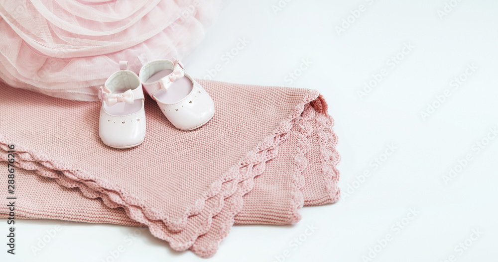 Pink baby plaid decorated with lace. Pink pillow lies nearby. White baby shoes stand on a plaid. Pink baby plaid decorated with lace. Pink pillow lies nearby. White baby shoes stand on a plaid.