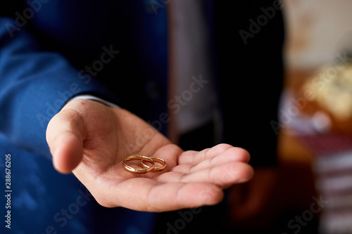 Groom holding wedding rings on the palm, wedding ring in groom hand..