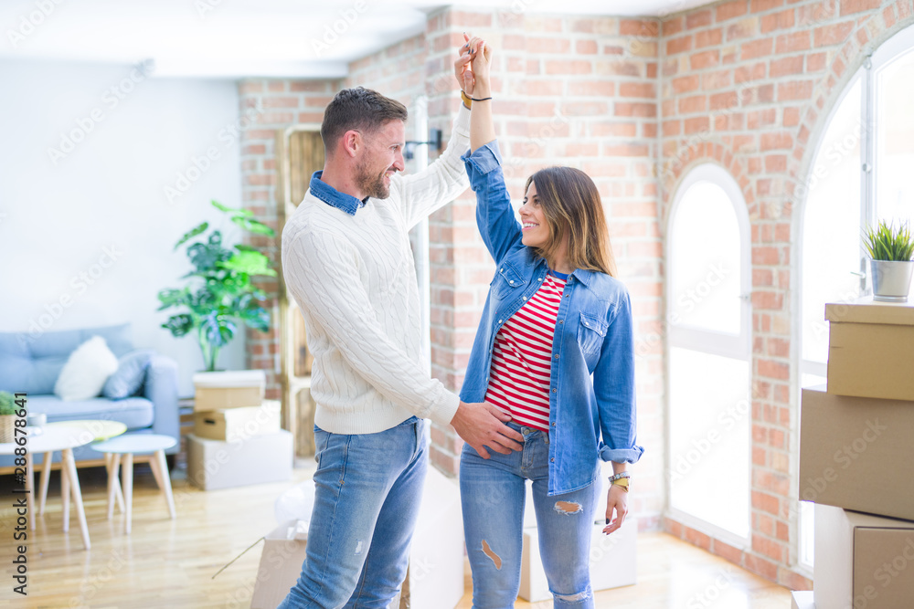 Young beautiful couple dancing at new home around cardboard boxes Young beautiful couple dancing at new home around cardboard boxes