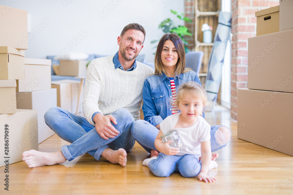 Beautiful family sitting on the floor playing with his kid at new home around cardboard boxes Beautiful family sitting on the floor playing with his kid at new home around cardboard boxes