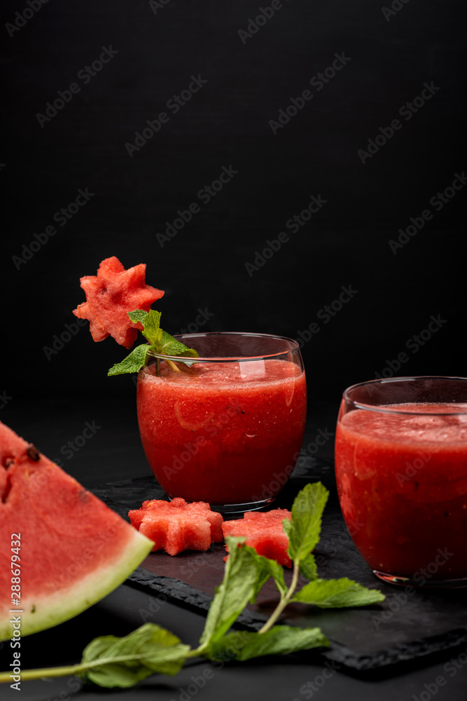 Watermelon smoothie fresh juice with mint and pieces in the shape of stars on a black background. Summer healthy drinks. Copy space. Watermelon smoothie fresh juice with mint and pieces in the shape of stars on a black background. Summer healthy drinks. Copy space.