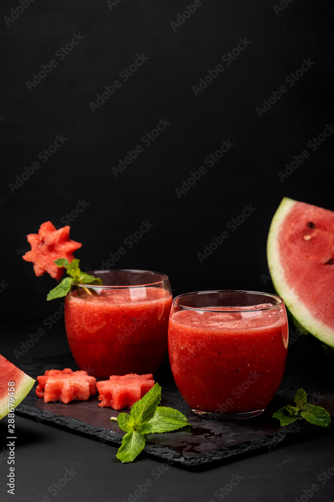 Watermelon smoothie fresh juice with mint and pieces in the shape of stars on a black background. Summer healthy drinks. Copy space. Watermelon smoothie fresh juice with mint and pieces in the shape of stars on a black background. Summer healthy drinks. Copy space.
