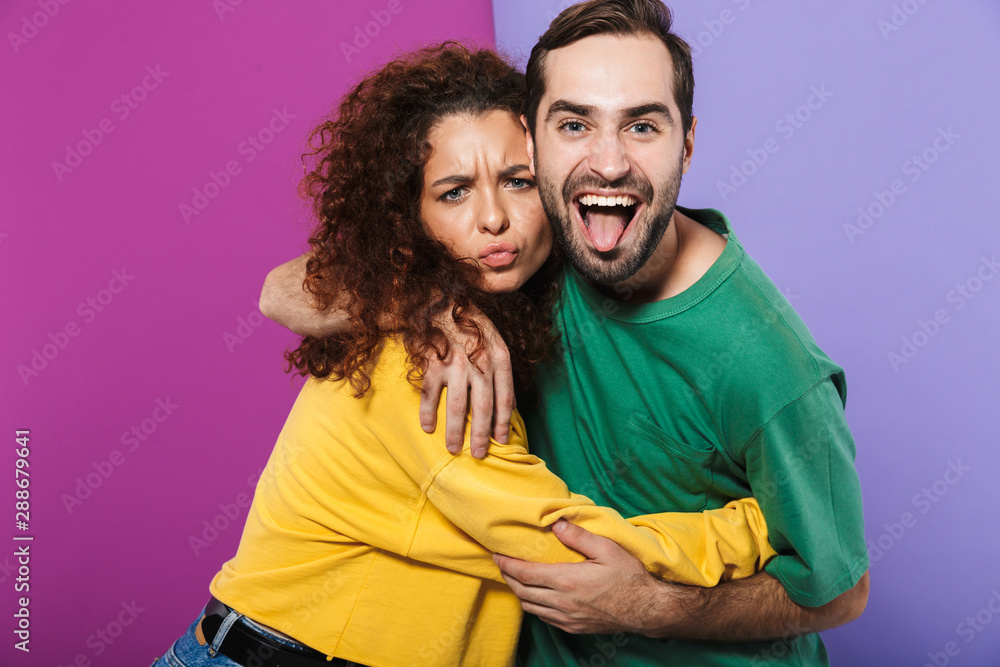 Portrait of happy caucasian couple man and woman in colorful clothing rejoicing and hugging together Portrait of happy caucasian couple man and woman in colorful clothing rejoicing and hugging together