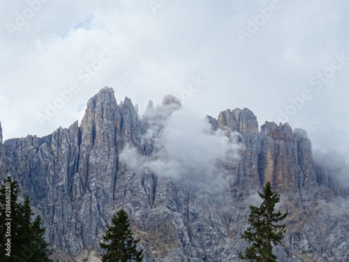 The Latemar Massif, one of the most spectacular peaks of the Dolomites seen from the woods of Trentino, near the village of Carezza, Italy - August 2019.