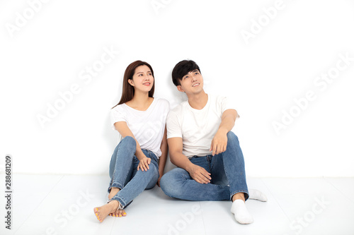 Happy Young Couple Sitting On Floor Looking Up