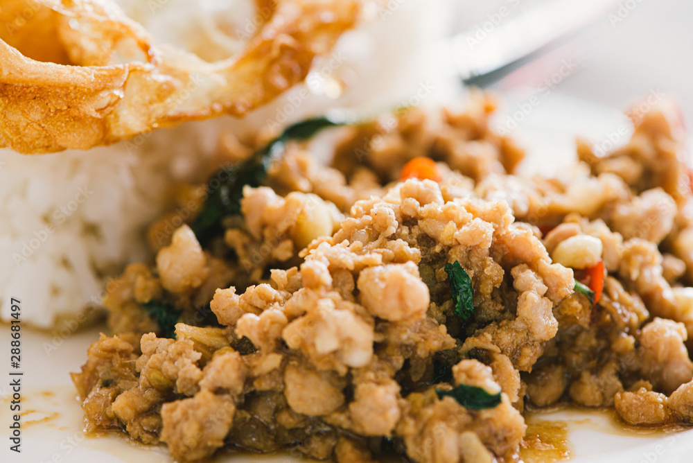 Spicy pork with basil leaf and rice on top with fried egg in white plate. Spicy pork with basil leaf and rice on top with fried egg in white plate.
