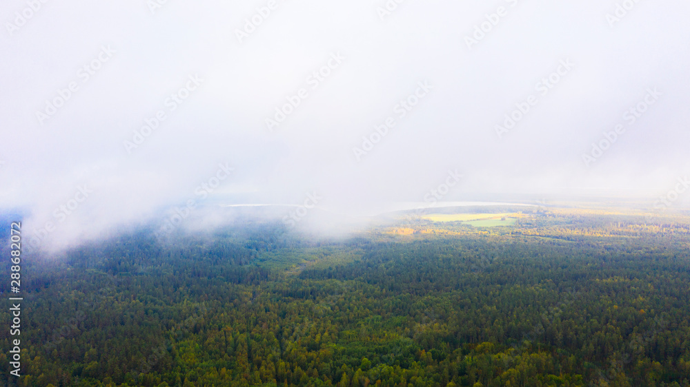 Aerial Drone view clouds over the green forest and lake. Low lying cloud. Aerial view of over tropical rainforest. Above the clouds in the sky. Top view from drone