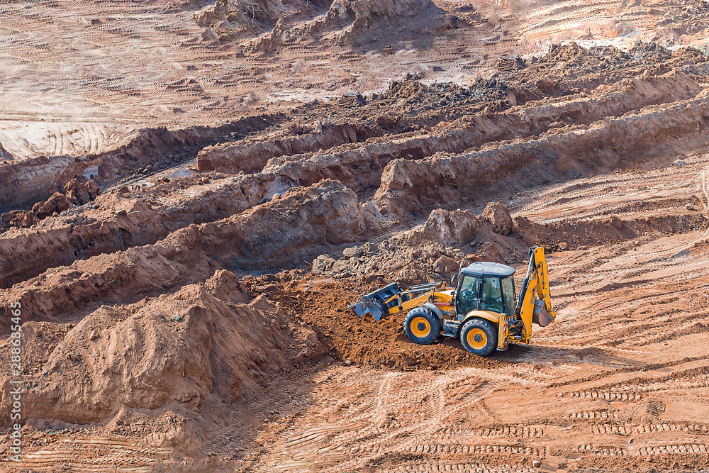 Wheel loader excavator machine working in construction site. wheel loader at sandpit during earthmoving works Wheel loader excavator machine working in construction site. wheel loader at sandpit during earthmoving works