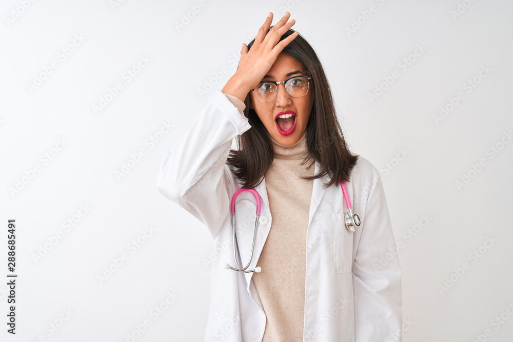 Chinese doctor woman wearing coat and pink stethoscope over isolated white background surprised with hand on head for mistake, remember error. Forgot, bad memory concept. Chinese doctor woman wearing coat and pink stethoscope over isolated white background surprised with hand on head for mistake, remember error. Forgot, bad memory concept.