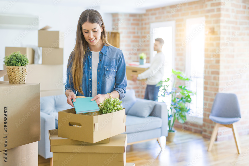 Young couple moving to a new home, beautiful woman smiling moving cardboard box Young couple moving to a new home, beautiful woman smiling moving cardboard box