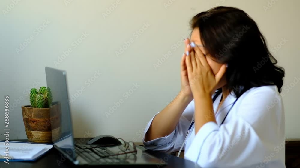 Close up of unknown female doctor sitting at the table in hospital and typing at laptop computer. Young Woman Doctor Nurse in Hospital Clinic Office. Close up of unknown female doctor sitting at the table in hospital and typing at laptop computer. Young Woman Doctor Nurse in Hospital Clinic Office.