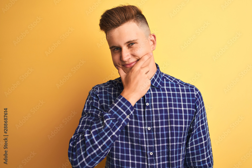 Young handsome man wearing casual shirt standing over isolated yellow background looking confident at the camera smiling with crossed arms and hand raised on chin. Thinking positive. Young handsome man wearing casual shirt standing over isolated yellow background looking confident at the camera smiling with crossed arms and hand raised on chin. Thinking positive.