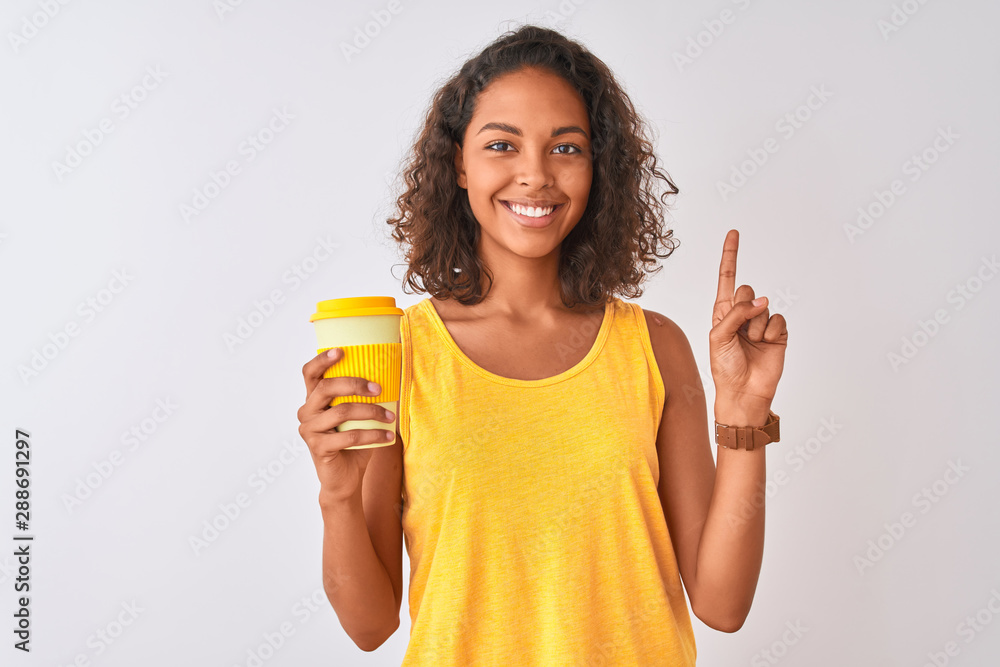 Young brazilian woman drinking take away coffee standing over isolated white background surprised with an idea or question pointing finger with happy face, number one Young brazilian woman drinking take away coffee standing over isolated white background surprised with an idea or question pointing finger with happy face, number one