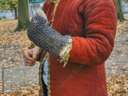 Obraz na płótnie ćwiczenia szermiercze rekonstruktora walk rycerskich, zakładanie rękawicy z plecionki, walki i turnieje rycerskie wymagają ćwiczeń i sprawności, czerwony kaftan rycerski w salonie