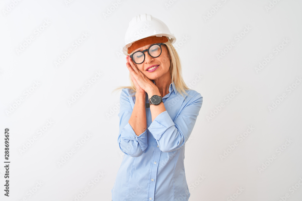 Middle age architect woman wearing glasses and helmet over isolated white background sleeping tired dreaming and posing with hands together while smiling with closed eyes. Middle age architect woman wearing glasses and helmet over isolated white background sleeping tired dreaming and posing with hands together while smiling with closed eyes.