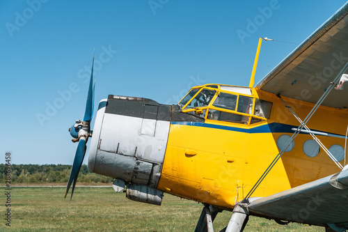 Vintage aircraft on green grass and blue sky background in sunlight. Old retro airplane