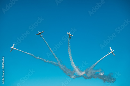 Airplanes with white smoke traces on air show. Pilots make tricks on jets at blue sky background