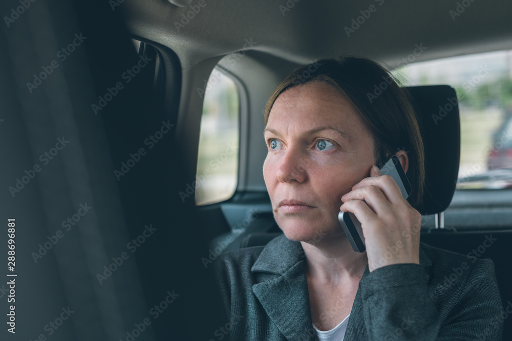 Businesswoman talking on mobile phone on car back seat Businesswoman talking on mobile phone on car back seat