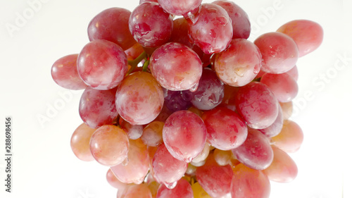 Pink grapes in drops of water on a light background. Closeup.