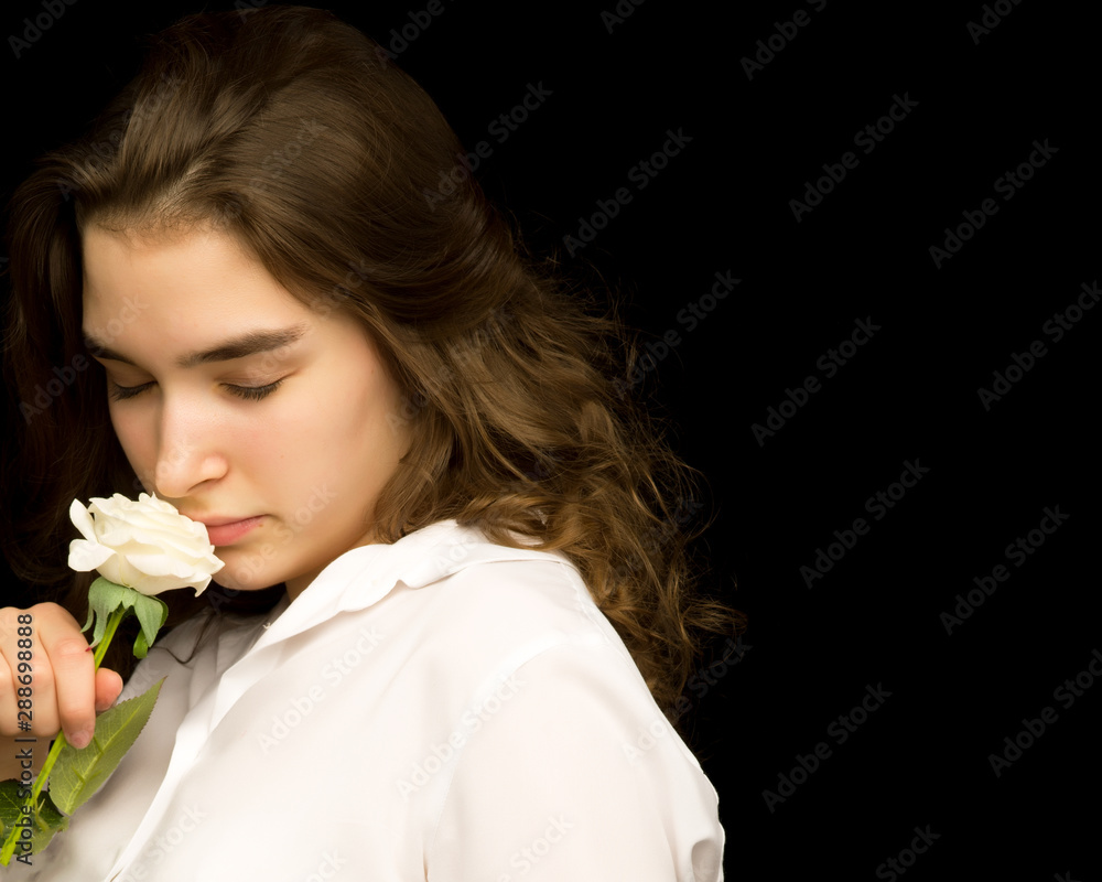 Naklejka premium Little girl with a white flower on a black background.