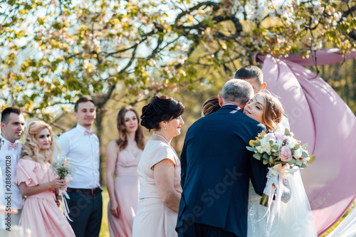 Bride and groom after wedding ceremony. Parents welcome newlyweds to marry. Stylish happy smiling newlyweds on the outdoor
